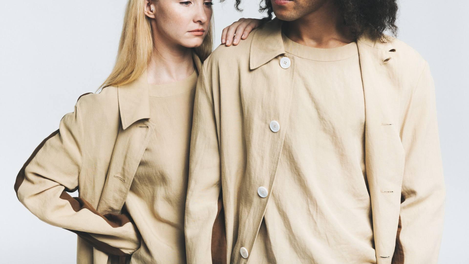 Two models stand side by side while wearing earth tone sustainable clothing made from bamboo fibers.